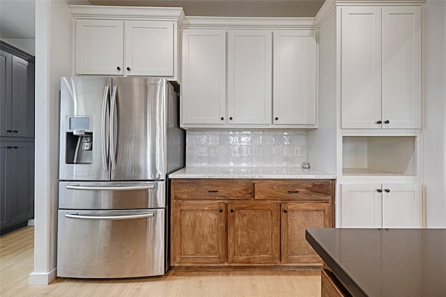 kitchen featuring white cabinets, backsplash, stainless steel fridge, and light hardwood / wood-style floors