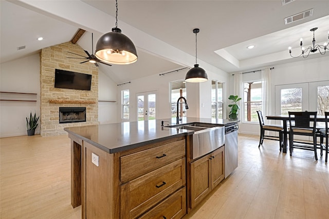 kitchen with dishwasher, decorative light fixtures, french doors, an island with sink, and light hardwood / wood-style floors