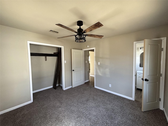 unfurnished bedroom featuring ceiling fan, ensuite bath, a closet, and dark carpet