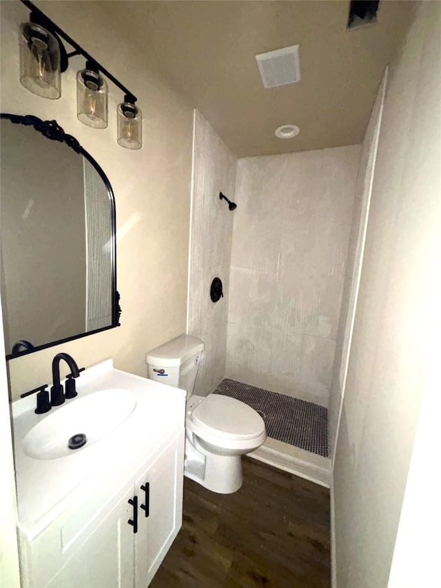 bathroom with toilet, a shower, hardwood / wood-style floors, and vanity