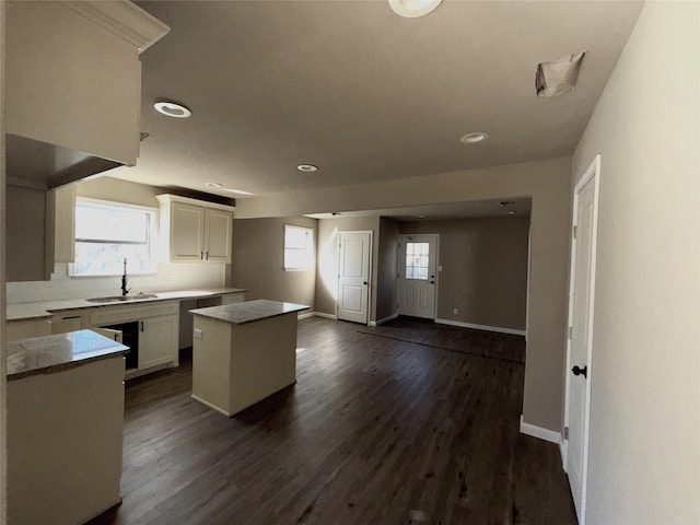 kitchen with dark wood-type flooring, sink, white cabinetry, and a center island