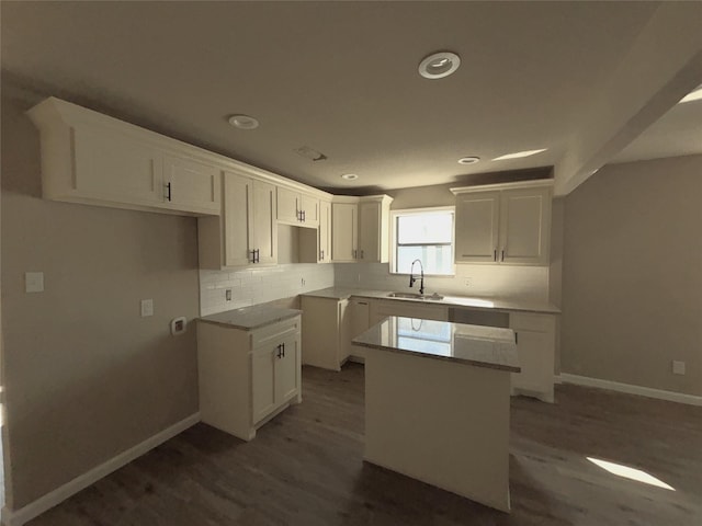 kitchen featuring sink, white cabinets, tasteful backsplash, and a center island