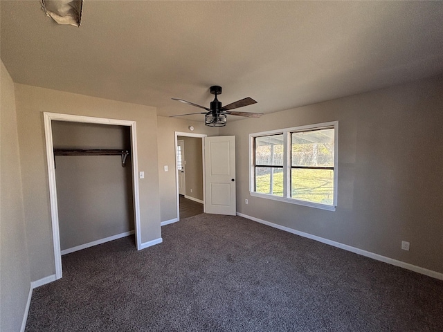 unfurnished bedroom with ceiling fan, dark carpet, and a closet