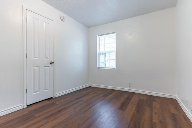 empty room featuring dark hardwood / wood-style floors and a textured ceiling