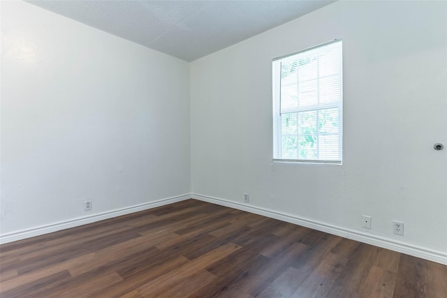 spare room with dark hardwood / wood-style floors and plenty of natural light