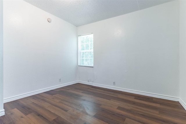 spare room featuring dark wood-type flooring and a textured ceiling