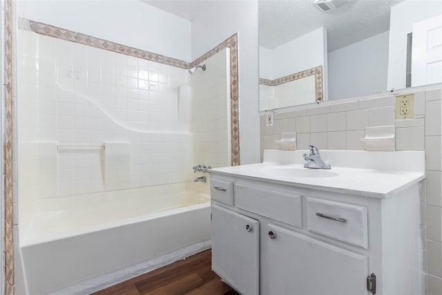 bathroom with tub / shower combination, a textured ceiling, vanity, decorative backsplash, and hardwood / wood-style flooring