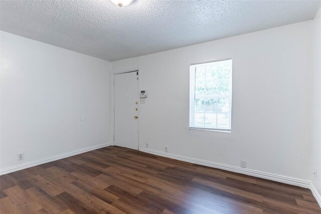 empty room with a textured ceiling and dark hardwood / wood-style floors