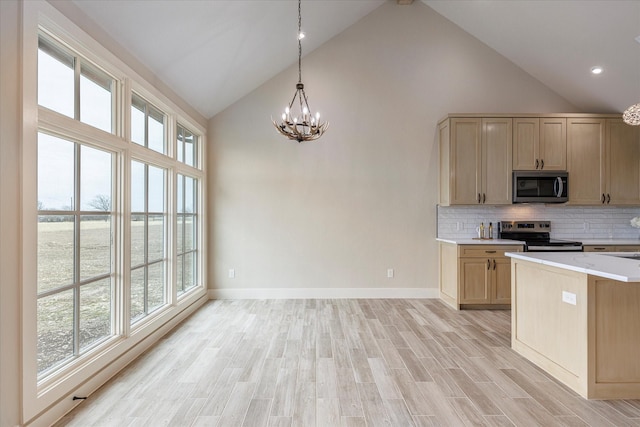 kitchen with light hardwood / wood-style floors, appliances with stainless steel finishes, light brown cabinets, backsplash, and decorative light fixtures