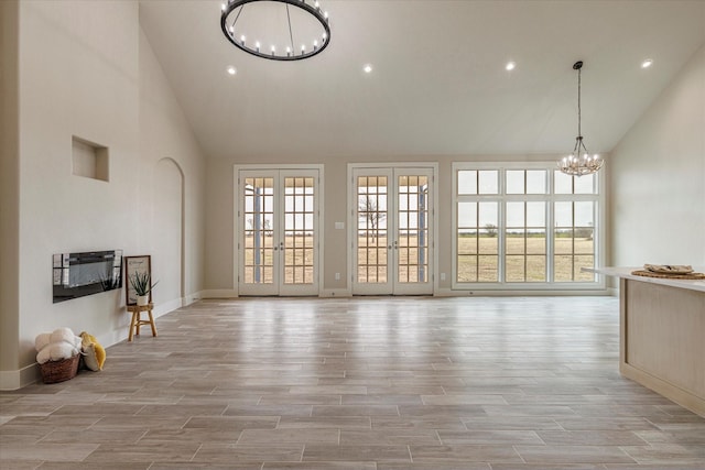 unfurnished living room featuring a towering ceiling, french doors, and a notable chandelier