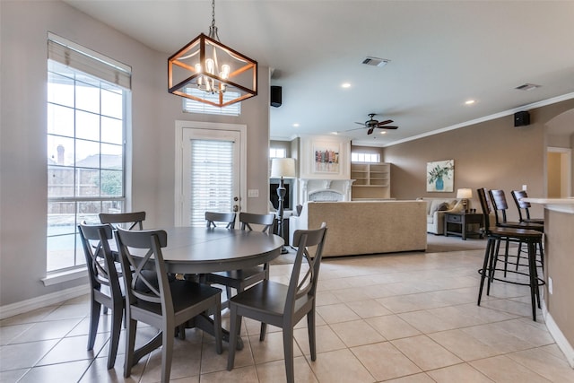 tiled dining room featuring ceiling fan with notable chandelier and crown molding