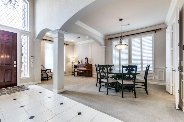 carpeted dining room with a healthy amount of sunlight, ornamental molding, and ornate columns