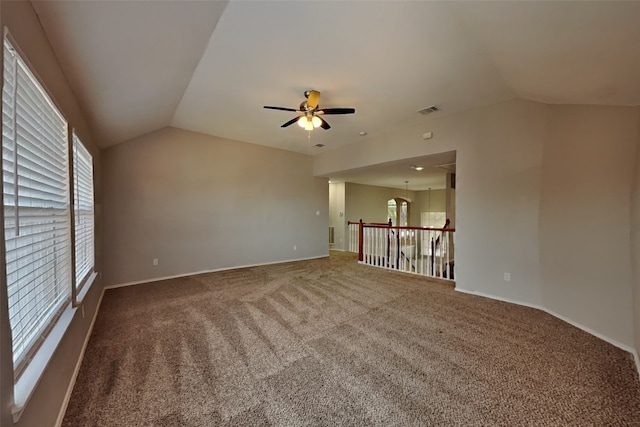 carpeted spare room featuring vaulted ceiling and ceiling fan