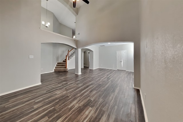 unfurnished living room with ceiling fan, dark wood-type flooring, and a high ceiling