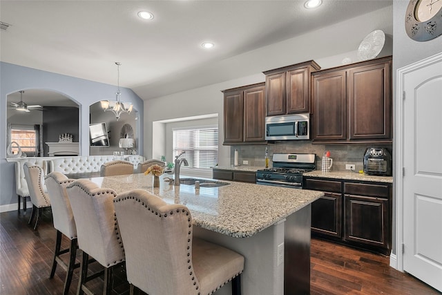 kitchen with pendant lighting, stainless steel appliances, an island with sink, sink, and dark brown cabinets