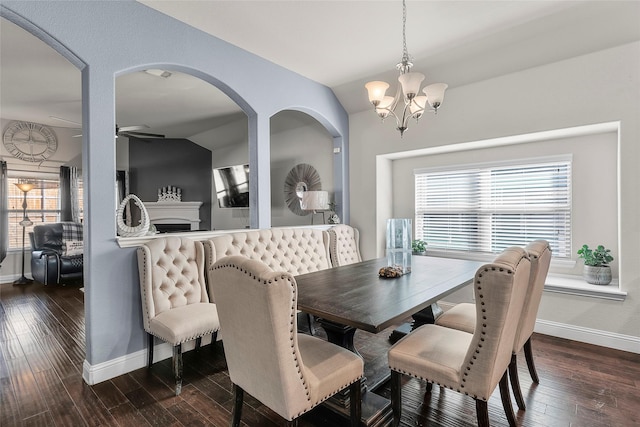 dining space with vaulted ceiling, ceiling fan with notable chandelier, and dark hardwood / wood-style flooring