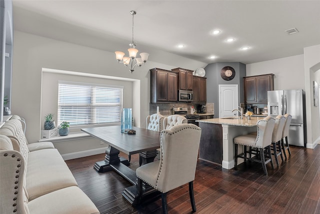 dining room with sink, dark hardwood / wood-style floors, and a notable chandelier