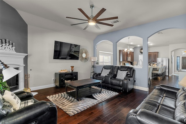 living room with ceiling fan with notable chandelier and dark wood-type flooring