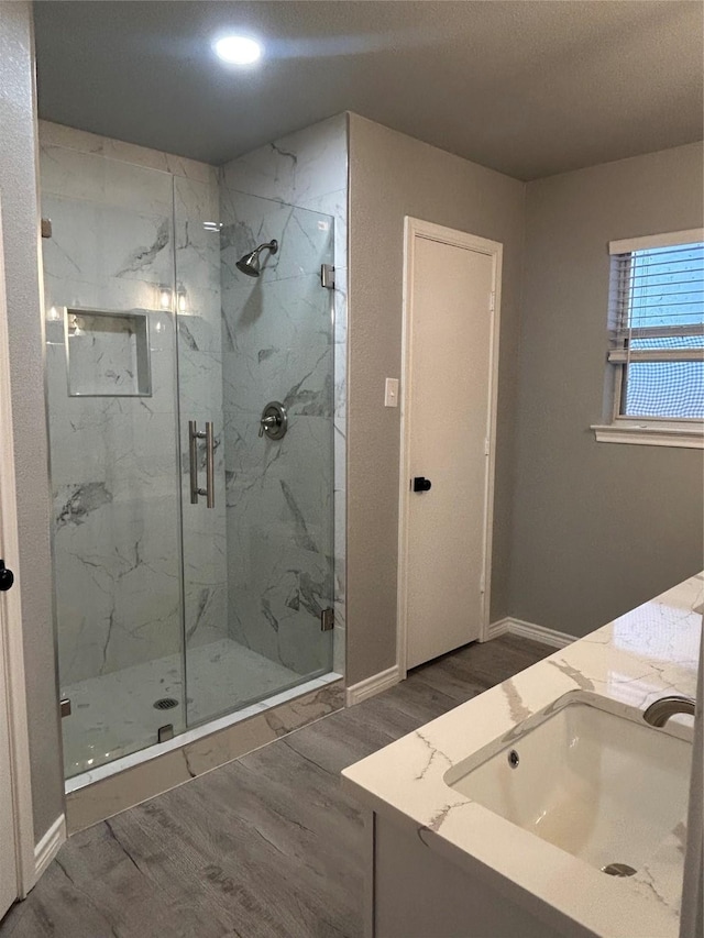 bathroom with hardwood / wood-style flooring, walk in shower, and vanity