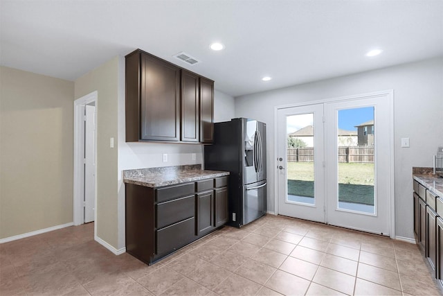 kitchen with dark brown cabinets, light tile patterned flooring, and stainless steel refrigerator with ice dispenser