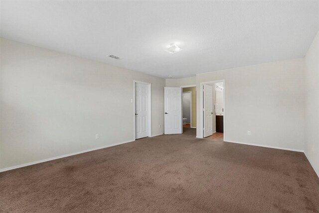 unfurnished bedroom with carpet floors, ensuite bath, visible vents, and baseboards