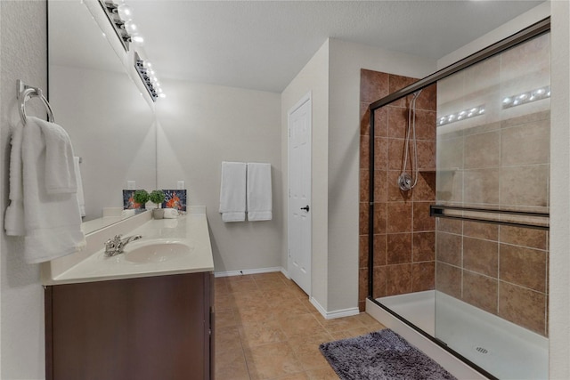 bathroom featuring a textured ceiling, vanity, baseboards, a shower stall, and tile patterned floors