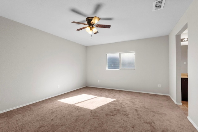 empty room featuring a ceiling fan, visible vents, light carpet, and baseboards