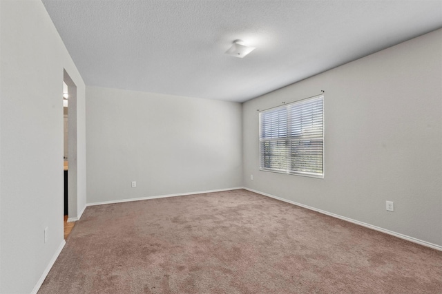 empty room with a textured ceiling, carpet, and baseboards