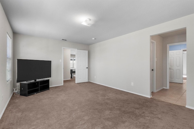 unfurnished living room featuring carpet floors, visible vents, and baseboards