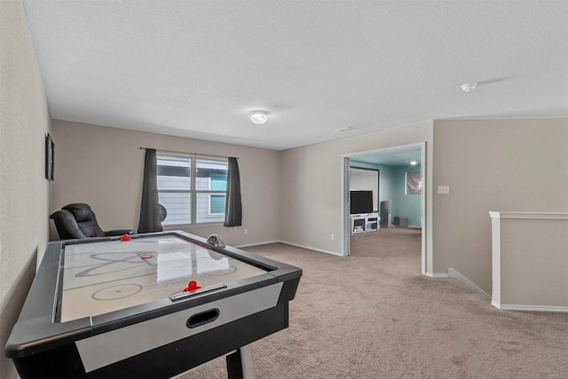 recreation room with light colored carpet, a textured ceiling, and baseboards