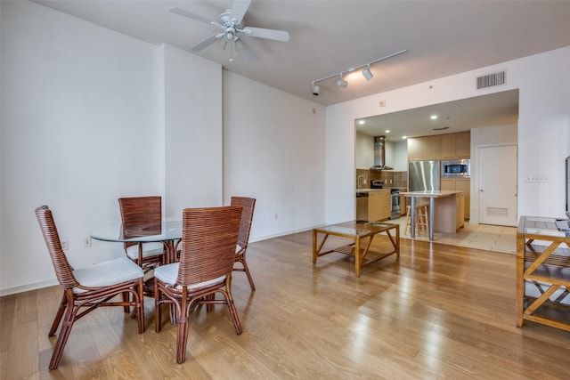 dining area with light hardwood / wood-style floors, track lighting, and ceiling fan