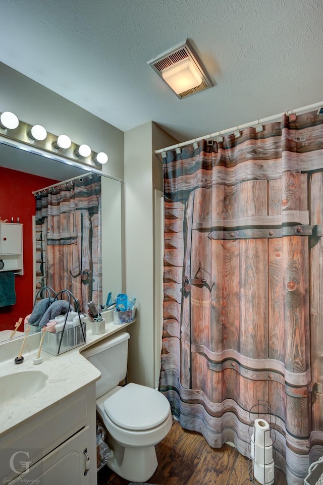 bathroom featuring curtained shower, a textured ceiling, wood-type flooring, vanity, and toilet