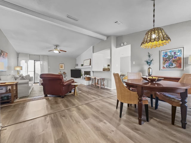 dining area with hardwood / wood-style flooring, ceiling fan, and vaulted ceiling with beams