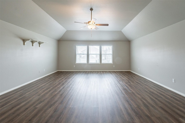 interior space featuring ceiling fan, vaulted ceiling, and dark wood-type flooring