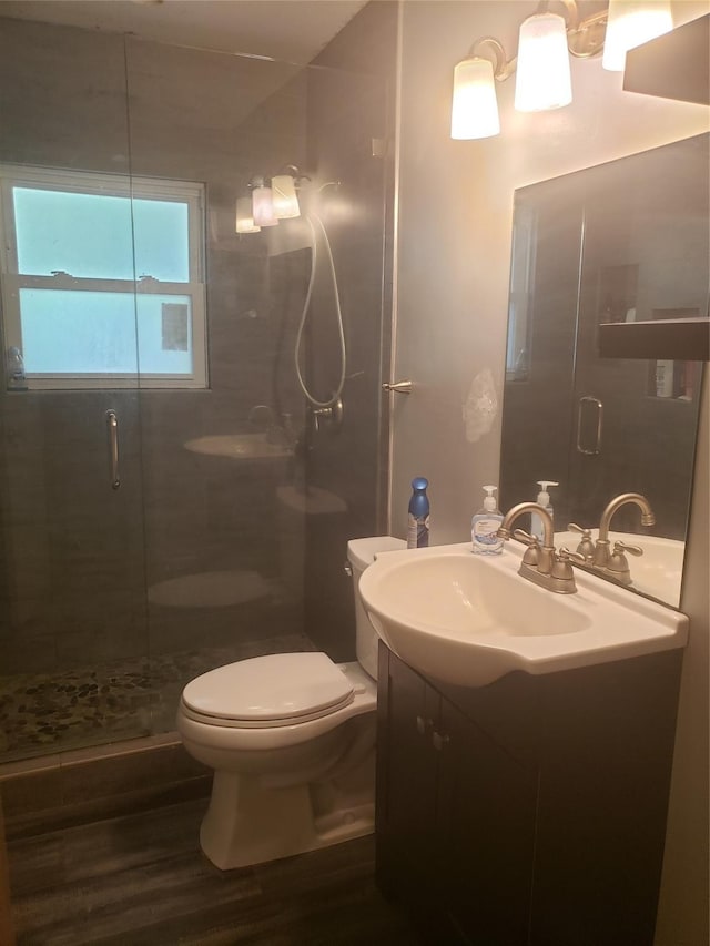 bathroom with toilet, vanity, a shower with door, and hardwood / wood-style floors