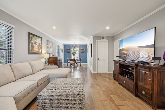 living room with a chandelier, light hardwood / wood-style flooring, and ornamental molding