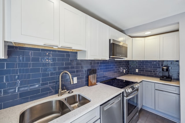 kitchen with sink, backsplash, white cabinetry, light stone countertops, and stainless steel appliances