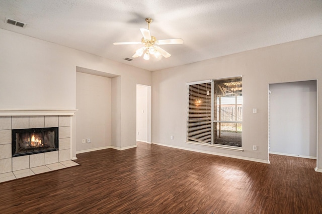 unfurnished living room with ceiling fan, hardwood / wood-style floors, a textured ceiling, and a fireplace