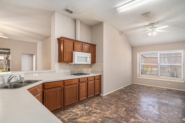 kitchen featuring lofted ceiling, sink, gas cooktop, ceiling fan, and decorative backsplash