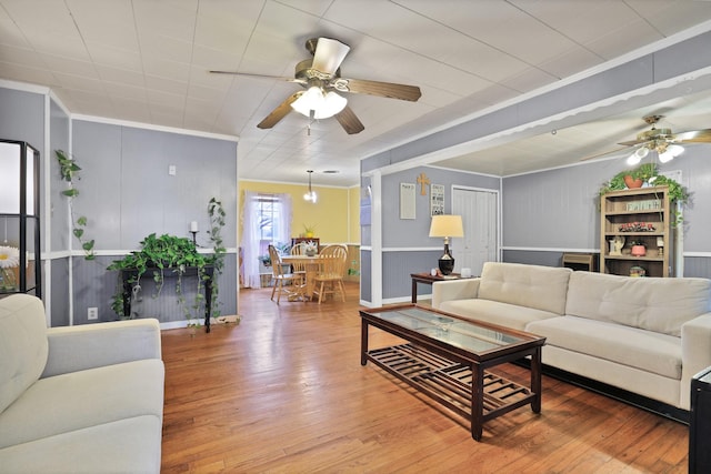 living room with hardwood / wood-style flooring, ornamental molding, and ceiling fan