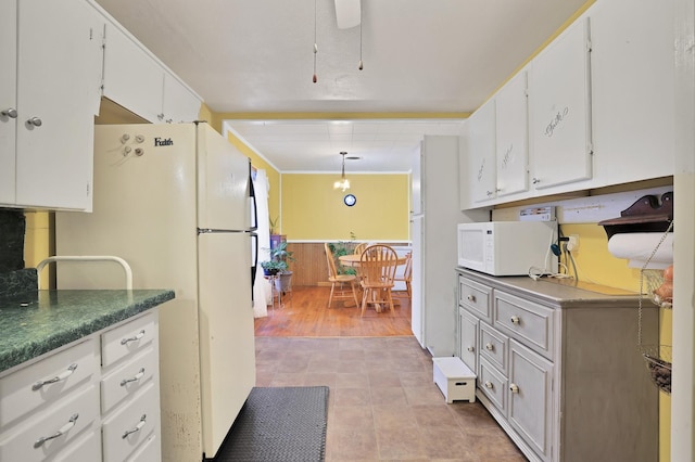 kitchen with decorative light fixtures, white appliances, and white cabinetry