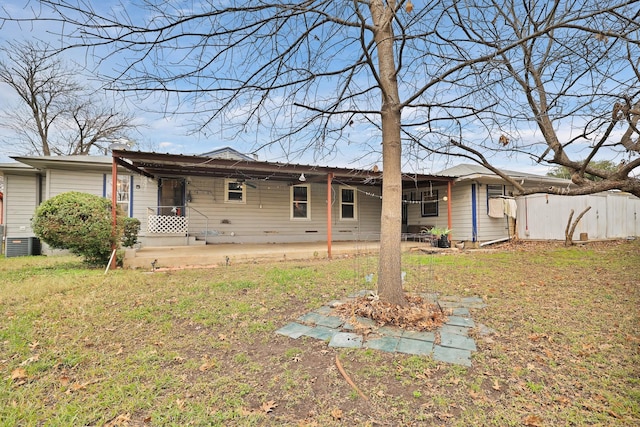 rear view of property with central AC and a yard