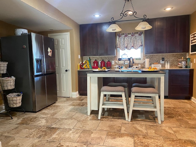 kitchen featuring decorative light fixtures, stainless steel fridge, and dark brown cabinets