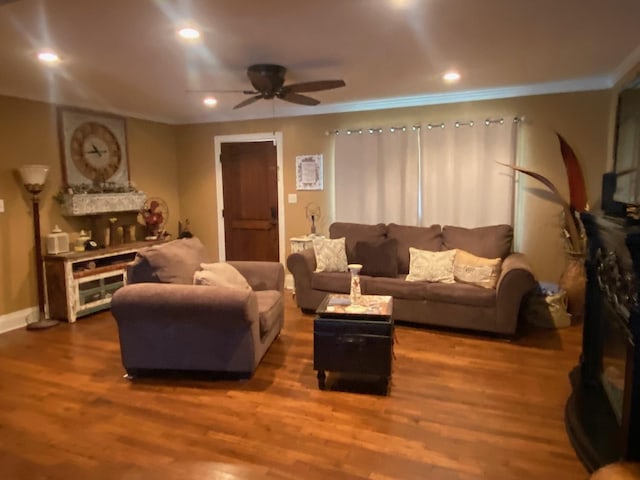 living room with ceiling fan, a large fireplace, dark hardwood / wood-style floors, and crown molding