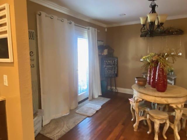 dining room with dark wood-type flooring, ornamental molding, and a notable chandelier