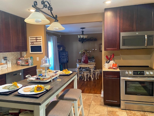 kitchen featuring light tile patterned floors, appliances with stainless steel finishes, decorative backsplash, hanging light fixtures, and crown molding