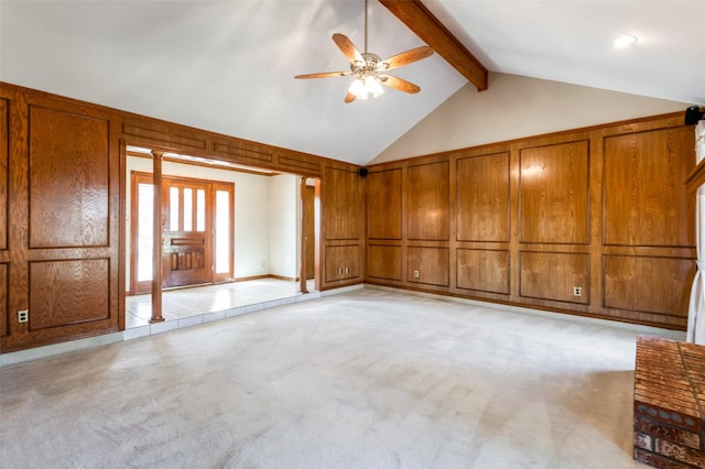 unfurnished living room featuring wood walls, ceiling fan, light colored carpet, high vaulted ceiling, and beamed ceiling