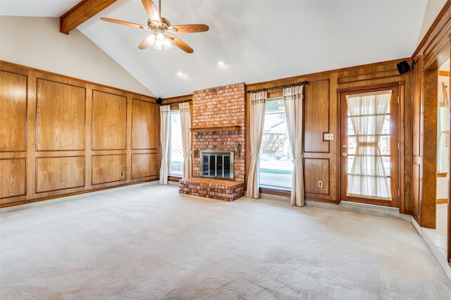 unfurnished living room featuring wood walls, a brick fireplace, light carpet, and vaulted ceiling with beams