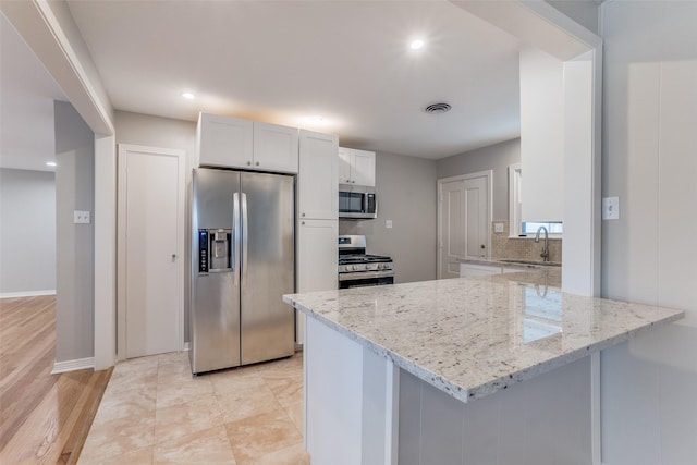 kitchen featuring decorative backsplash, sink, light stone countertops, stainless steel appliances, and white cabinets