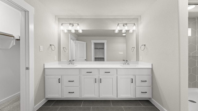 bathroom with double vanity, tiled shower, and a sink